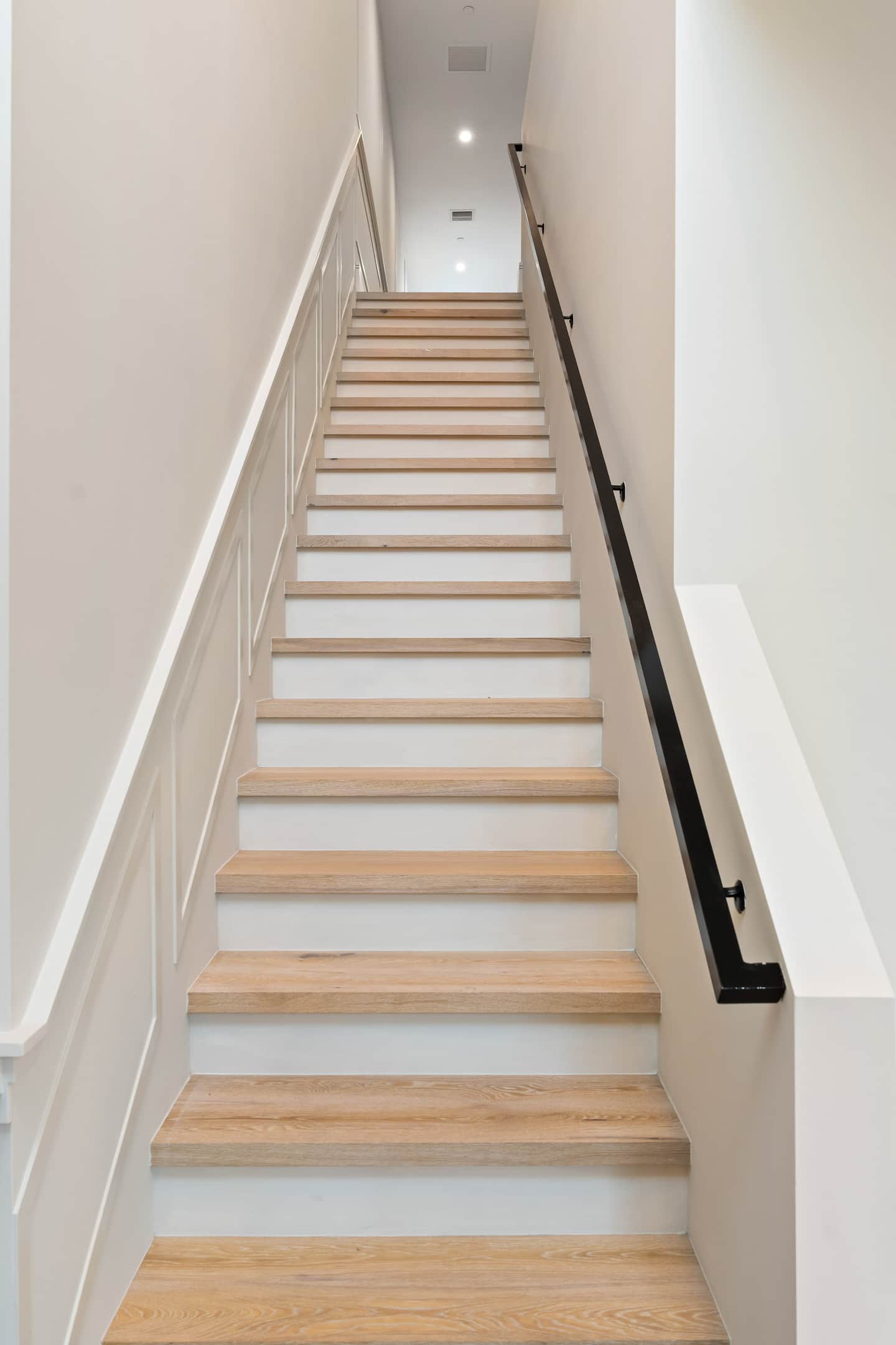 Light wood staircase with black handrail