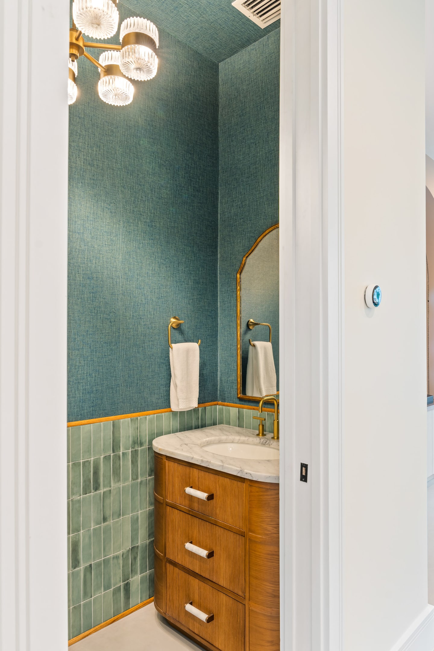 Bathroom vanity with green tile and brass details